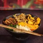 Delicious bibimbap in a black bowl.