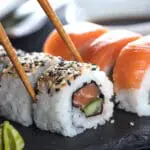 Delicious sushi being picked up with chopsticks.