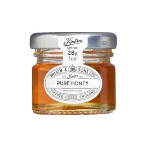 Small glass jar of Tiptree Pure Clear Honey Portions Pots 72x28g isolated on a white background.