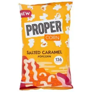 A package of Propercorn Salted Caramel Popcorn 24x28g against a white background, featuring a vibrant orange and yellow design with popcorn and caramel graphics.