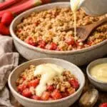 Freshly baked rhubarb and strawberry crumble made with forced rhubarb, topped with golden oat crumble and served with vanilla custard, recipe by Nicol Retailer