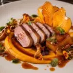 Michelin-star maple-glazed duck breast with roasted butternut squash three ways, burnt orange jus, pickled chanterelles and pumpkin seed brittle on an elegant fine-dining plate