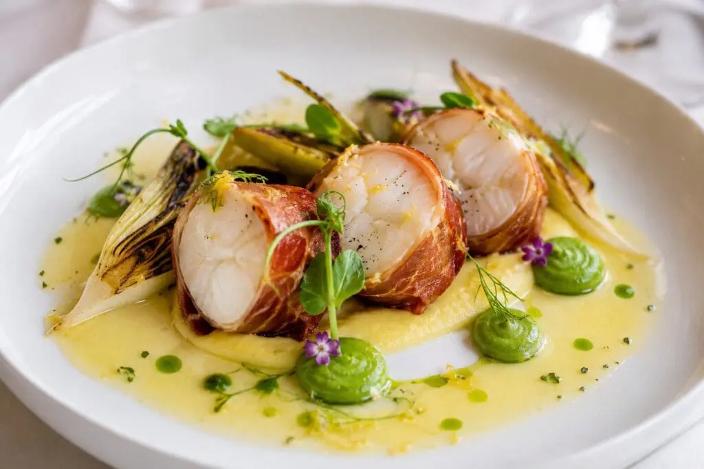 Michelin-inspired San Michele Speck-crusted monkfish with saffron cauliflower velouté, pea purée, charred leeks and Champagne beurre blanc, created by Nicol Retailer Limited