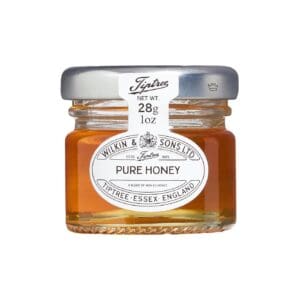 Small glass jar of Tiptree Pure Clear Honey Portions Pots 72x28g isolated on a white background.