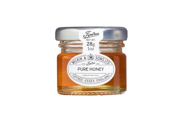 Small glass jar of Tiptree Pure Clear Honey Portions Pots 72x28g isolated on a white background.