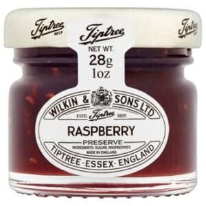 A small jar of Tiptree Raspberry Preserve 72x28g with a white lid and a label indicating it is produced by Wilkin & Sons Ltd. in Tiptree-Essex, England.