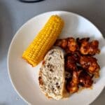 Corn, chicken, and bread on a plate.