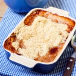 Baked gooseberry crumble in blue dish.