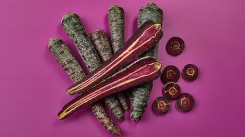 Purple carrots and slices on purple.