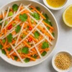 Bowl of fresh mooli and carrot salad with sesame seeds, coriander, and lemon dressing by Nicol Retailer Limited