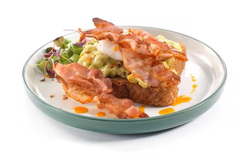 Avocado smash spread over golden sourdough toast with lemon and seasoning