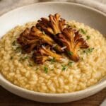 Creamy maitake mushroom risotto topped with crispy golden-brown mushrooms, parmesan, and thyme butter, served in a rustic ceramic bowl. Created by Nicol Retailer Limited using premium Maitake Mushrooms 500g.