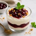 Warm Morello cherry compote served over vanilla mascarpone cream in a glass, garnished with mint and chocolate shavings. Image and recipe created by Nicol Retailer Limited.