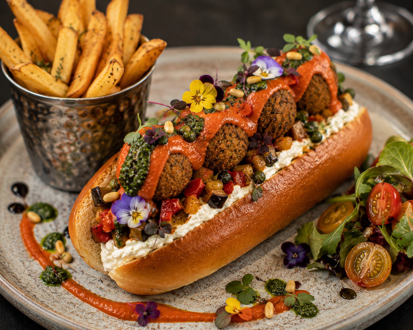 Michelin-Star Mediterranean Falafel Brioche Roll filled with crispy falafel, Provençal ratatouille, whipped vegan feta, roasted red pepper coulis, basil pistou and fresh herbs in a toasted La Boulangerie Vegan Brioche Style Hot Dog Roll.